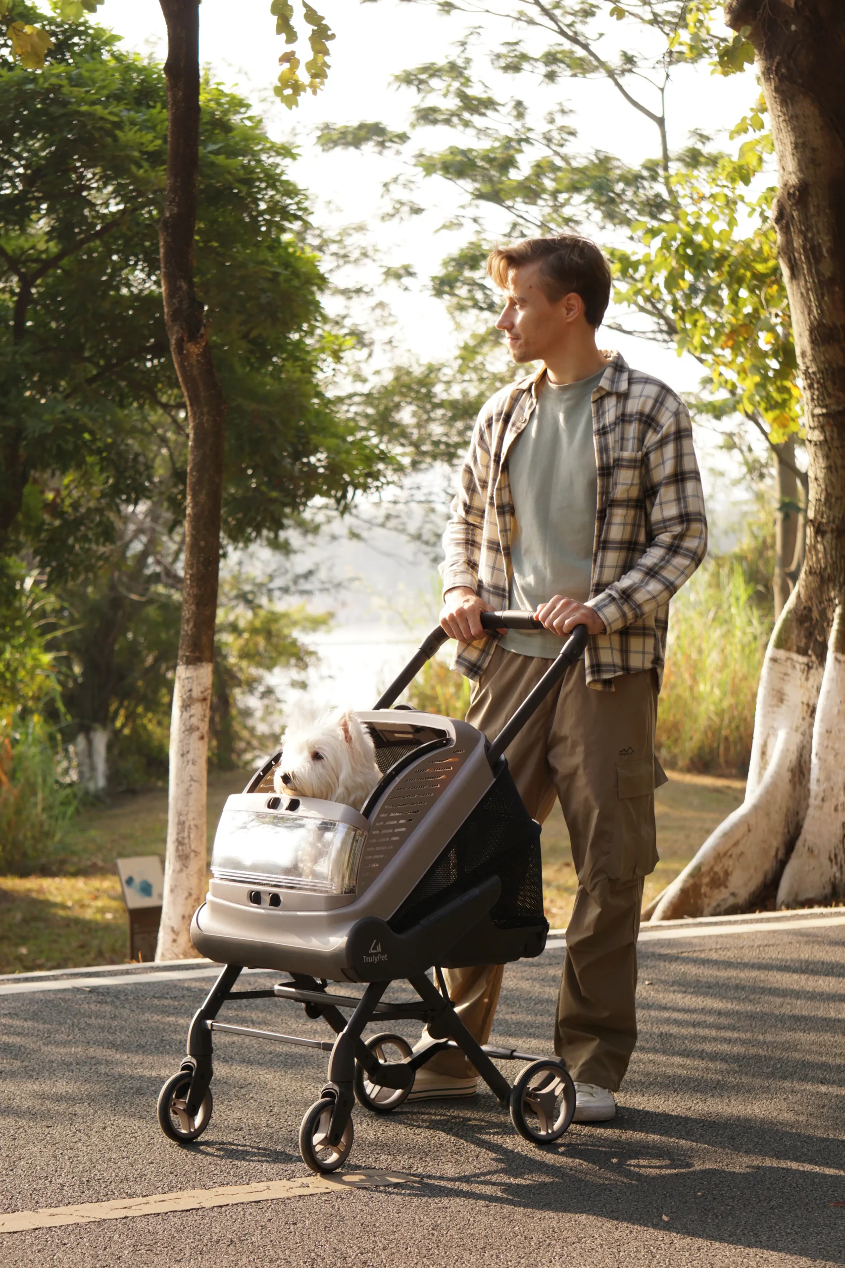 Man pushing the TrulyPet Explorer pet stroller along a lakeside path with a dog inside